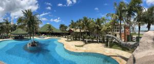 a resort with a large swimming pool with palm trees at Porto Marina Resort in Ilha Comprida