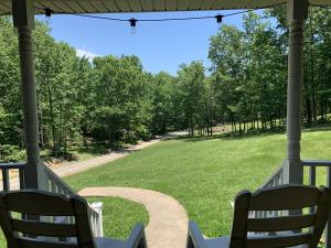 a porch with two chairs and a field of grass at Old Wagon Lodge Spacious Retreat WiFi & Hot Tub Theater Room in Luray