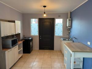 a small kitchen with a black door and a counter at Casa independiente muy acogedora in Puerto Varas