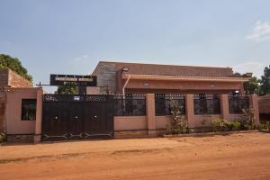 a house with a black gate and a building at Freetown Resort-Gulu in Gulu