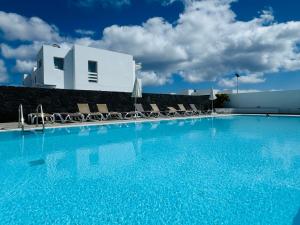 a large swimming pool with chairs and a building at Casa Noa by Vulcano Homes in Costa Teguise