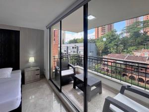 a hotel room with a balcony with a bed and a chair at 4br 232 M Apartment In El Poblado, El Tesoro in Medellín
