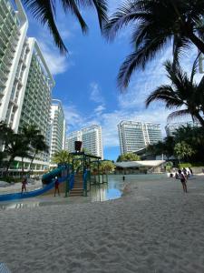 a playground on a beach with tall buildings at Azure Staycation PH 1503 in Manila