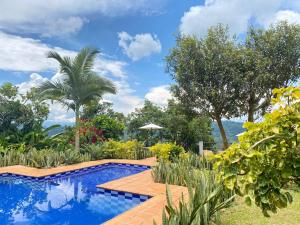 a swimming pool in a garden with a wooden deck at Tierra Mágica eje cafetero in Manizales