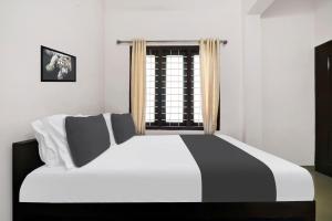 a black and white bed in a room with a window at Hotel O GRAND RESIDENCY in Ambalapulai