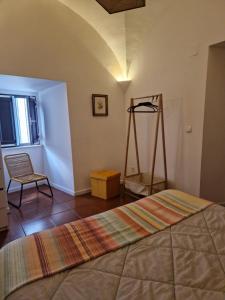 a bedroom with a bed and a chair in a room at Casa do Arco II in Évora