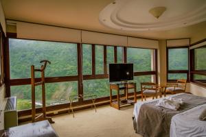 a bedroom with a bed and a tv and some windows at Hotel Spa Termas de Reyes in San Salvador de Jujuy