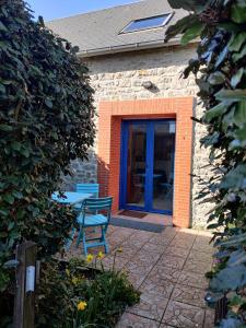 ein Gebäude mit einer blauen Tür und einer Terrasse in der Unterkunft Escapade cotentine in Montmartin-sur-Mer