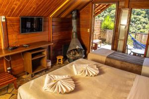 a room with two beds and a fireplace in a cabin at Pousada Olivier da Montanha - Recanto das Águas in Santo Antônio do Pinhal