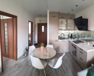 a kitchen with a table and some white chairs at Palerma Apartament in Darłowo