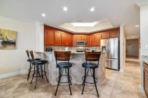 een keuken met een bar met 4 krukken bij The Oasis at Orange Beach 1813 (formerly known as Phoenix West II) in Romar Beach