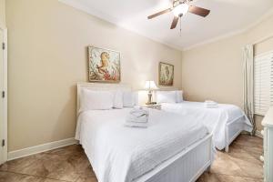 twee witte bedden in een kamer met een plafondventilator bij The Oasis at Orange Beach 1813 (formerly known as Phoenix West II) in Romar Beach