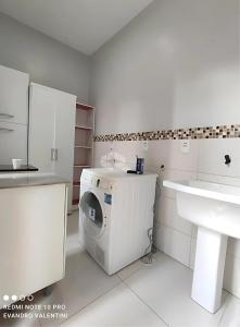 ein weißes Badezimmer mit einer Waschmaschine und einem Waschbecken in der Unterkunft Casa de Alto Padrão Verdes Campos POA in Porto Alegre + 22 Fotos