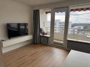 ein Wohnzimmer mit Flachbildfernseher und großem Fenster in der Unterkunft Ostsee Apartment mit Meerblick in Sierksdorf