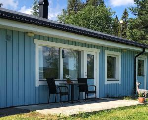 a blue house with a table and chairs on a patio at Sjönära lägenghet på landet in Fränsta +9 photos