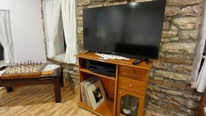 a flat screen tv on a wooden stand in a living room at Beautiful room with private bathroom in old city centre in Gjirokastër
