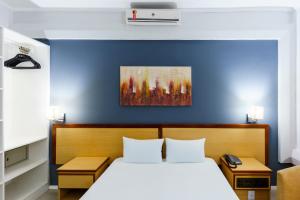 a bedroom with a bed and a blue wall at Hotel Augusta Boulevard in São Paulo +22 photos
