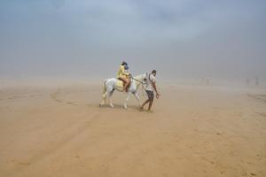 two people riding a horse in the desert at Hotel-Restaurant Le Kaouki in Sidi Kaouki
