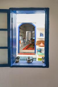 a blue window with a view of a room at Hotel-Restaurant Le Kaouki in Sidi Kaouki