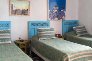 three beds in a room with blue and green at Hotel-Restaurant Le Kaouki in Sidi Kaouki