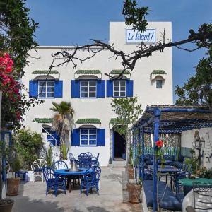 a building with blue tables and chairs in front of it at Hotel-Restaurant Le Kaouki in Sidi Kaouki