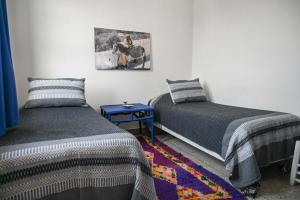 a bedroom with two beds and a painting on the wall at Hotel-Restaurant Le Kaouki in Sidi Kaouki