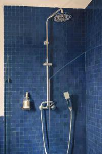 a blue tiled shower with a shower head in a bathroom at Hotel-Restaurant Le Kaouki in Sidi Kaouki