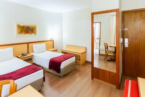 a hotel room with two beds and a table at Hotel Augusta Boulevard in São Paulo