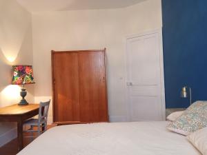 a bedroom with a bed and a desk and a cabinet at La petite Parenthèse in Hauterives