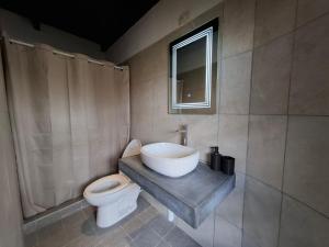 Un baño con lavabo, inodoro y ventana. en Volka Hotel, en Antigua Guatemala