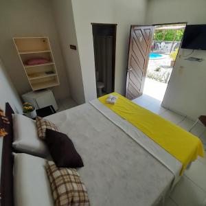 a bedroom with a large bed with a yellow blanket on it at Pousada Barra Mansa in Pitimbu