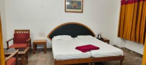 a bedroom with a bed with a red shirt on it at Hotel Shivasangam Residency in Bāgalkot +2 photos
