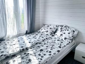 a bed with a black and white comforter and a window at Domki na Łące in Sarbinowo