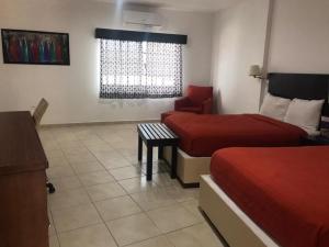 a hotel room with two beds and a chair at Hotel Marina Topolobampo in Topolobampo