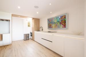 a kitchen with white cabinets and a painting on the wall at Mazet design vue mer 4 guests in Sainte-Maxime