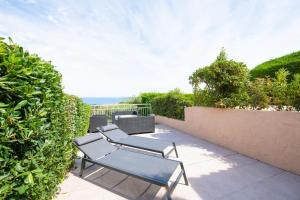 three chairs sitting on a patio next to a hedge at Mazet design vue mer 4 guests in Sainte-Maxime