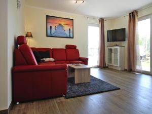 un salon avec un canapé rouge et une table dans l'établissement Appartement Hafenflair am Plauer See, à Plau am See
