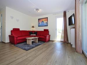 un salon avec un canapé rouge et une table dans l'établissement Appartement Hafenflair am Plauer See, à Plau am See