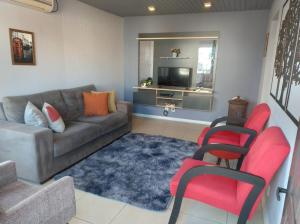 a living room with a couch and red chairs at Apartamento London - Centro Nova Petrópolis in Nova Petrópolis