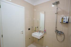 un bagno con lavandino e doccia con specchio di emBrace Apartments a Sarandë