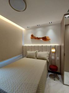 a bedroom with a large white bed and a red chair at Apartamento charmoso com Rooftop in Salvador