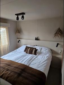 ein Schlafzimmer mit einem weißen Bett mit einem Kissen darauf in der Unterkunft La Casa Di Nyo - Camping De Schatberg in Sevenum