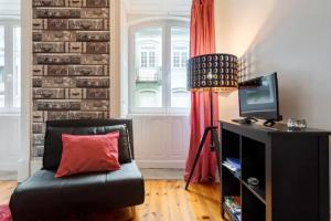 ein Wohnzimmer mit einem schwarzen Sofa und einem roten Kissen in der Unterkunft Almada e Fado in Porto