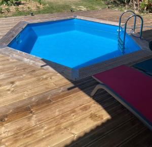a swimming pool on a deck with a wooden floor at Maison Créole in Anse-Bertrand