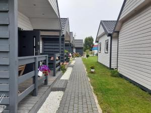a brick path between two houses with flowers on it at Błękitna Laguna 600m od morza in Rusinowo