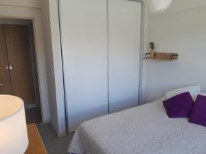 a bedroom with a white bed with purple pillows at Carocito Departamento in San Carlos de Bariloche