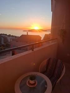 a balcony with a table and a view of the sunset at Apartman Luka, Przno in Pržno