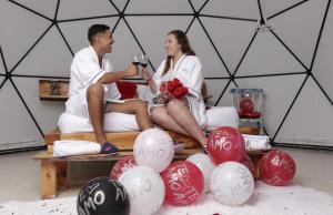 a man and a woman sitting on a bed with balloons at Amore Mio Glamping in Jenesano