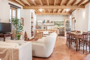 a living room with white furniture and a kitchen at Alla Torre del Barbarossa B&B FORESTERIA in Mandello del Lario