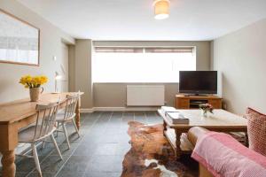 a living room with a table and a tv at Grooms Cottage in Weedon Bec
